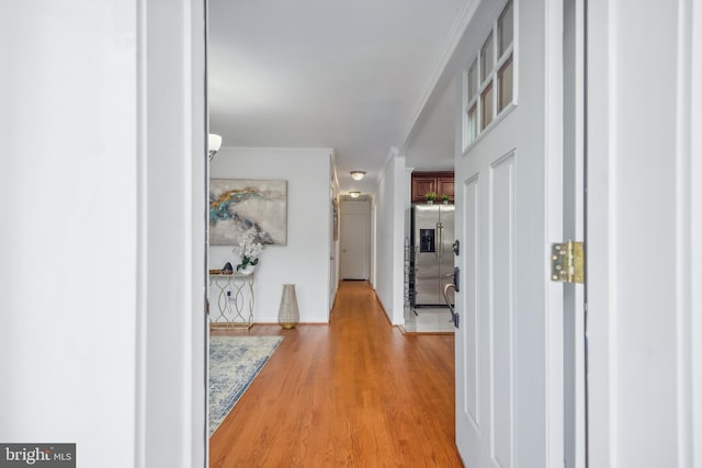 hall with light hardwood / wood-style flooring and crown molding