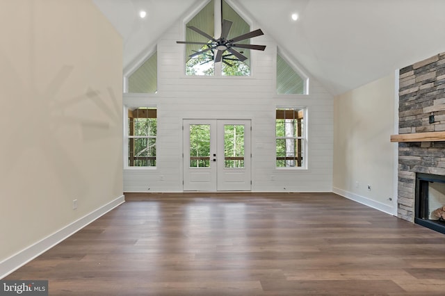 unfurnished living room with dark wood-type flooring, ceiling fan, high vaulted ceiling, a fireplace, and french doors