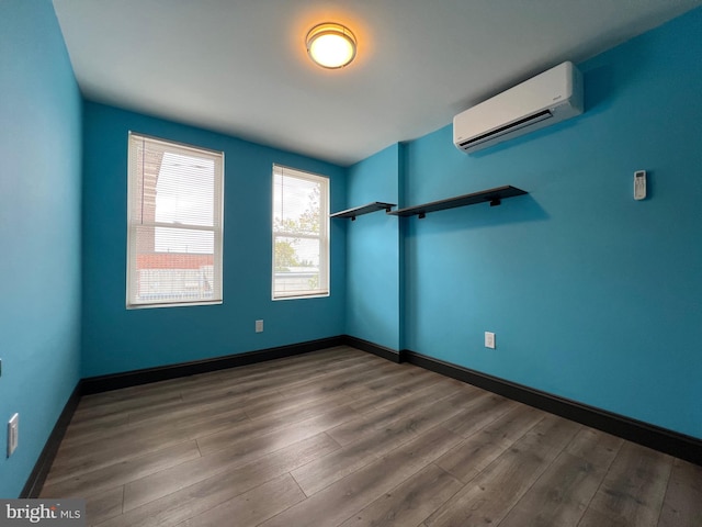 empty room with wood-type flooring and a wall mounted air conditioner