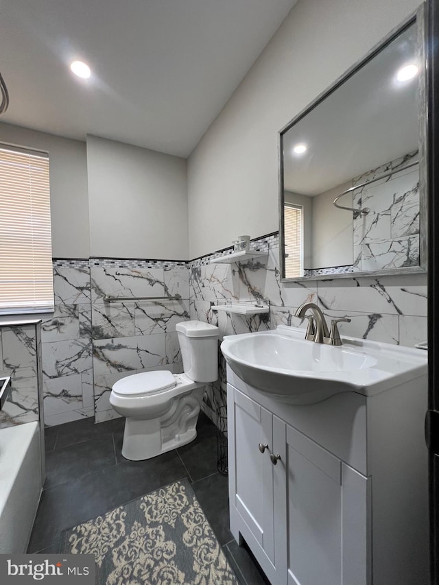 bathroom with tile walls, tile patterned flooring, a bathtub, vanity, and toilet