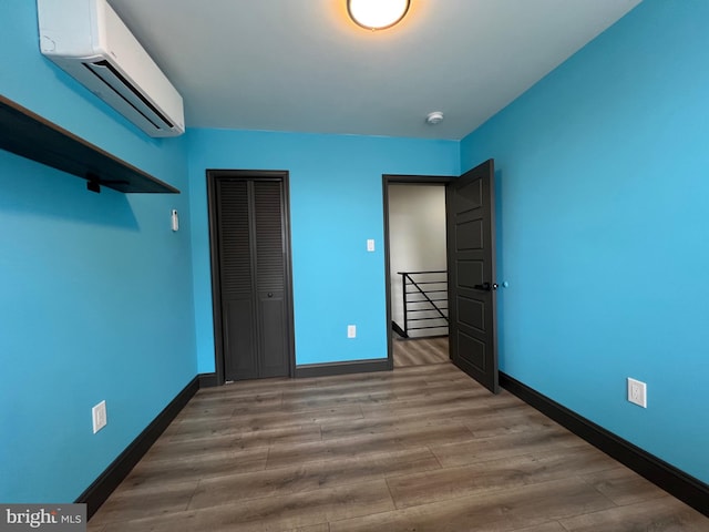 unfurnished bedroom with hardwood / wood-style flooring, a closet, and a wall mounted AC