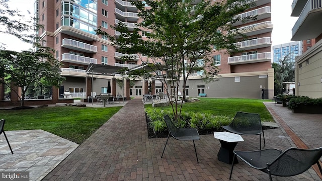 view of property's community featuring a lawn and a patio area