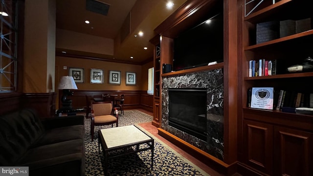 living area with a fireplace, ornamental molding, and built in shelves