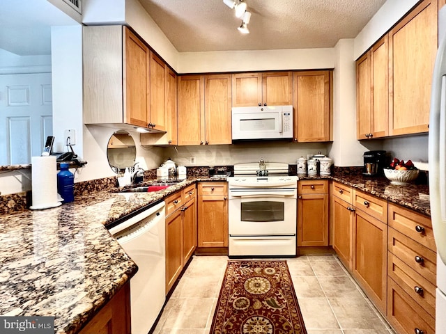 kitchen featuring light tile patterned floors, sink, white appliances, a textured ceiling, and dark stone countertops