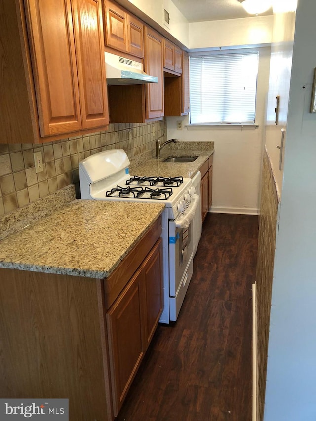 kitchen with sink, backsplash, white range with gas stovetop, dark hardwood / wood-style flooring, and light stone countertops