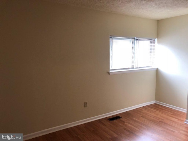 unfurnished room with light wood-type flooring and a textured ceiling