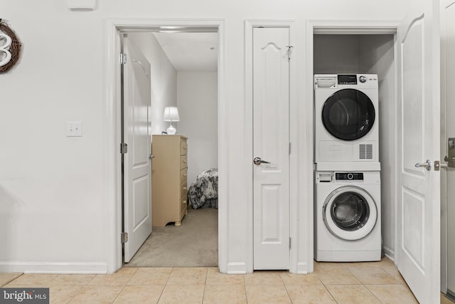 clothes washing area with light tile patterned floors and stacked washer / drying machine