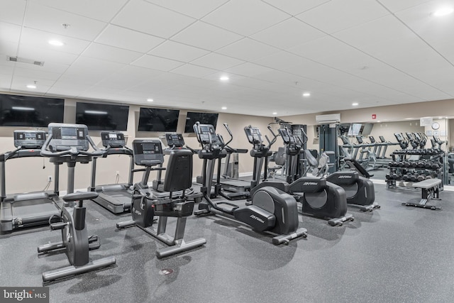 workout area with a paneled ceiling and a wall unit AC