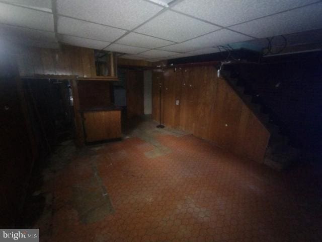 basement with wooden walls and a paneled ceiling