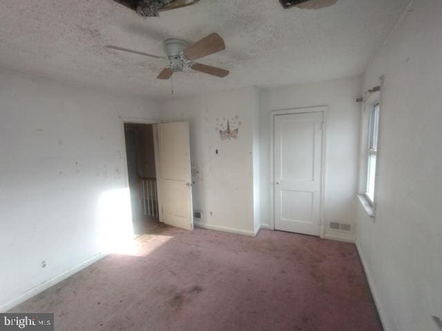 unfurnished bedroom featuring ceiling fan, light colored carpet, and a textured ceiling