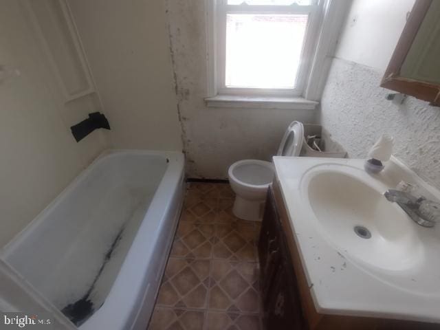 bathroom featuring vanity, toilet, and a washtub