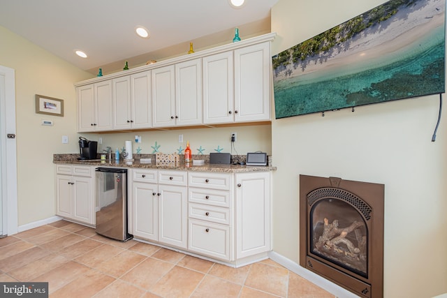 kitchen featuring white cabinets, dishwasher, light stone countertops, and light tile patterned floors