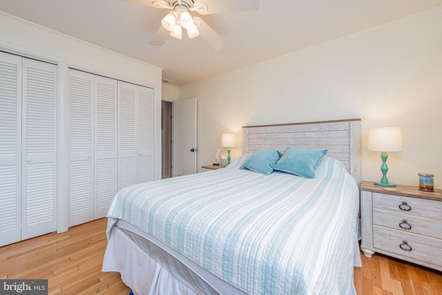 bedroom with ceiling fan, multiple closets, and light hardwood / wood-style floors