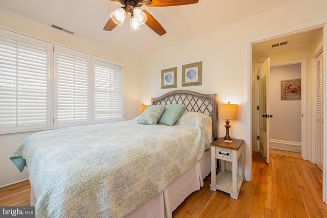 bedroom featuring light wood-type flooring, ornamental molding, and ceiling fan