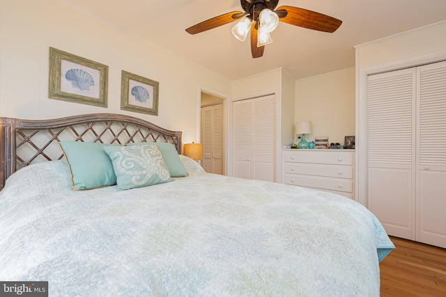 bedroom featuring multiple closets, light hardwood / wood-style floors, and ceiling fan