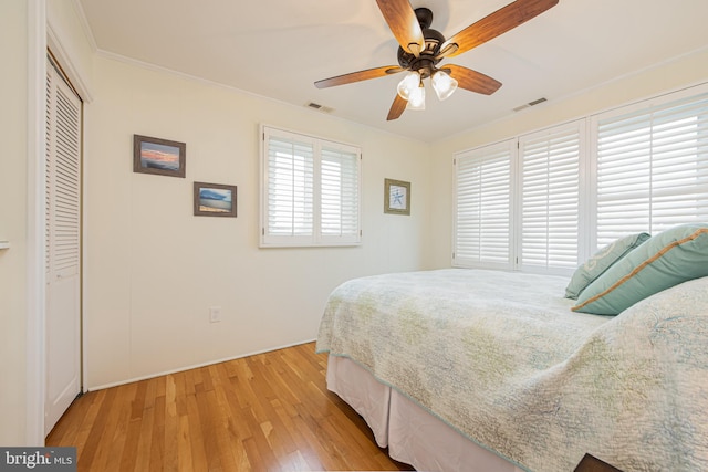 bedroom with light hardwood / wood-style flooring, ornamental molding, a closet, and ceiling fan