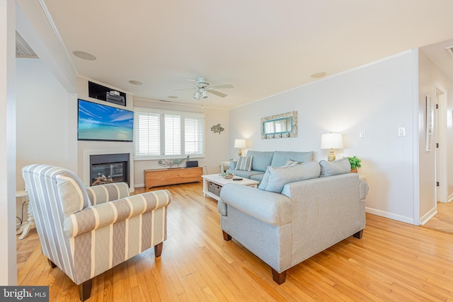 living room featuring crown molding, ceiling fan, and light hardwood / wood-style flooring