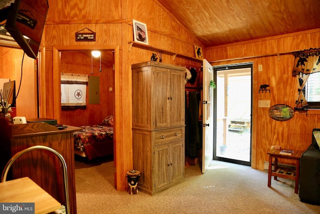 interior space with wooden walls, baseboard heating, wooden ceiling, vaulted ceiling, and light colored carpet