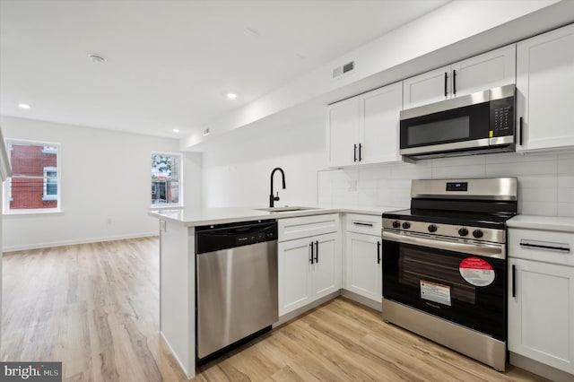 kitchen featuring white cabinets, appliances with stainless steel finishes, sink, and kitchen peninsula