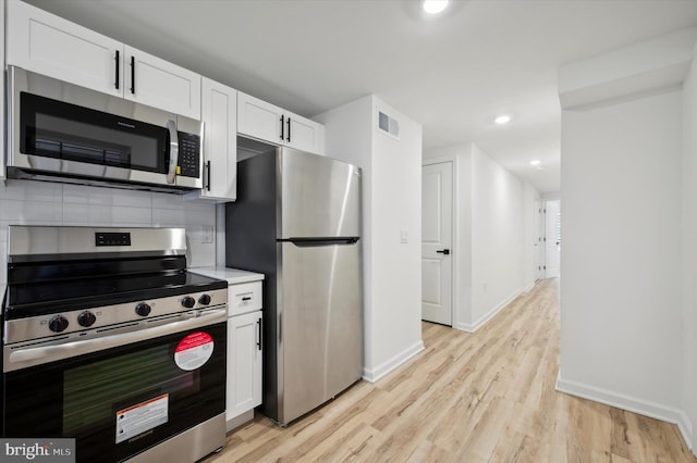 kitchen with light hardwood / wood-style flooring, appliances with stainless steel finishes, tasteful backsplash, and white cabinetry