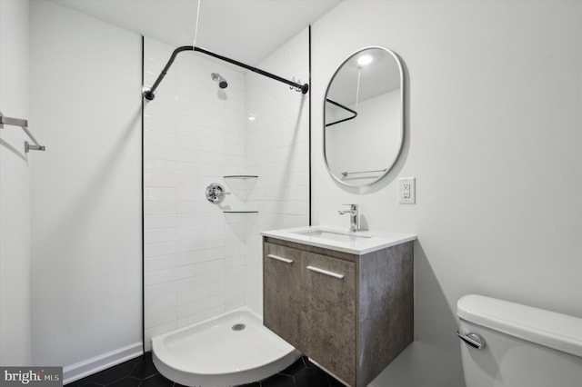 bathroom featuring a tile shower, tile patterned flooring, vanity, and toilet