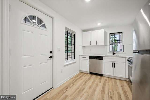 kitchen featuring appliances with stainless steel finishes, white cabinetry, sink, and plenty of natural light