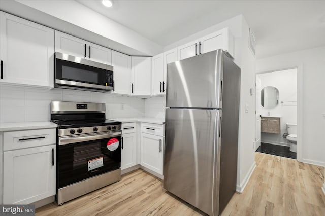 kitchen featuring light hardwood / wood-style flooring, stainless steel appliances, white cabinetry, and tasteful backsplash