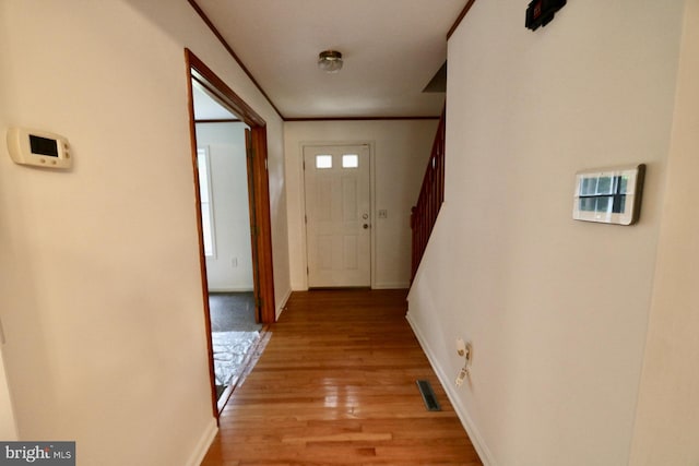 corridor with ornamental molding and light hardwood / wood-style floors