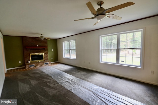 unfurnished living room featuring a healthy amount of sunlight, ceiling fan, dark carpet, and a fireplace