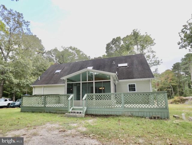 rear view of property featuring a yard, a wooden deck, and a sunroom