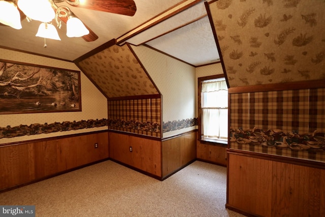 additional living space featuring light carpet, wood walls, and a textured ceiling