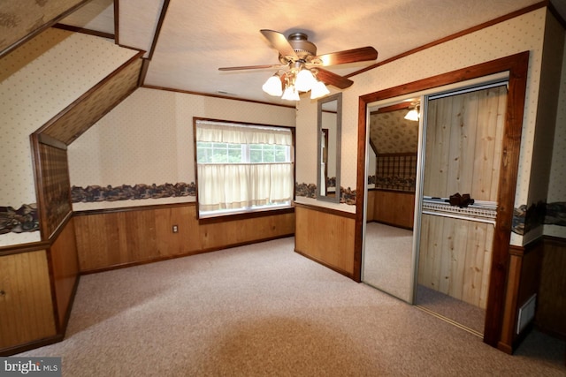 interior space with ceiling fan, a textured ceiling, wooden walls, and a closet