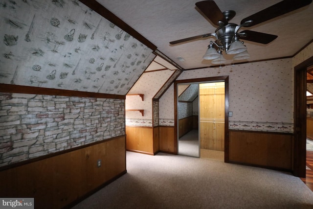 additional living space featuring ceiling fan, a textured ceiling, wood walls, and vaulted ceiling