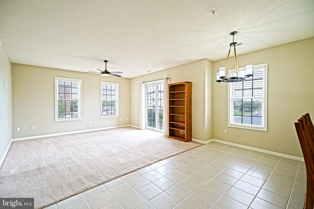 tiled empty room with ceiling fan with notable chandelier and a textured ceiling