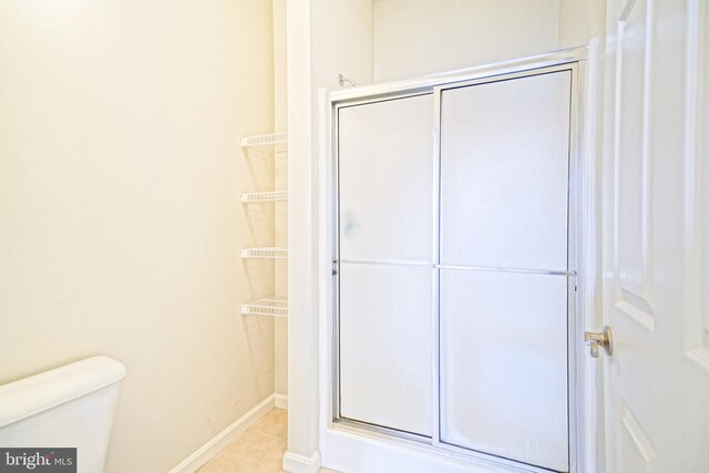 bathroom featuring tile patterned floors, toilet, and walk in shower