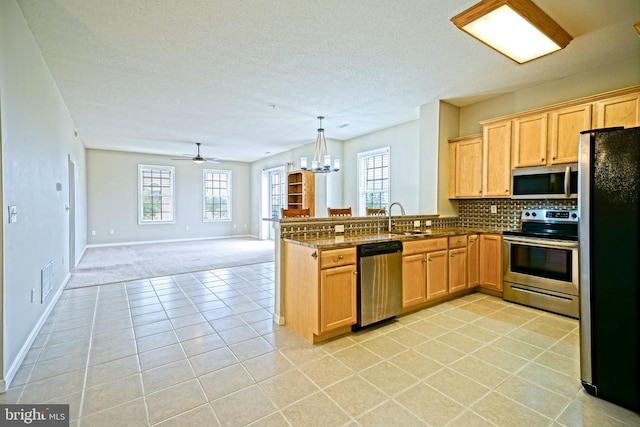 kitchen with stainless steel appliances, kitchen peninsula, decorative light fixtures, decorative backsplash, and light tile patterned flooring