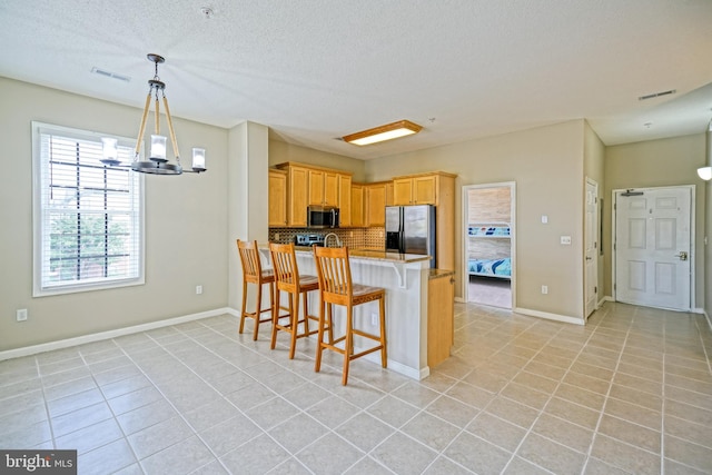 kitchen featuring kitchen peninsula, a kitchen breakfast bar, stainless steel appliances, light tile patterned floors, and a notable chandelier