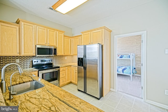 kitchen with decorative backsplash, light stone countertops, stainless steel appliances, sink, and light brown cabinets