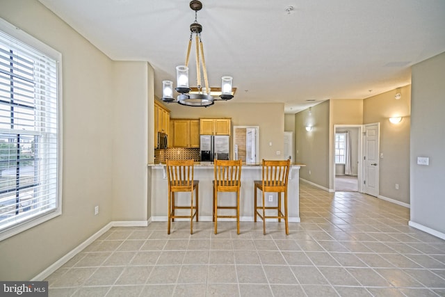 kitchen featuring a chandelier, stainless steel refrigerator with ice dispenser, light tile patterned floors, and plenty of natural light