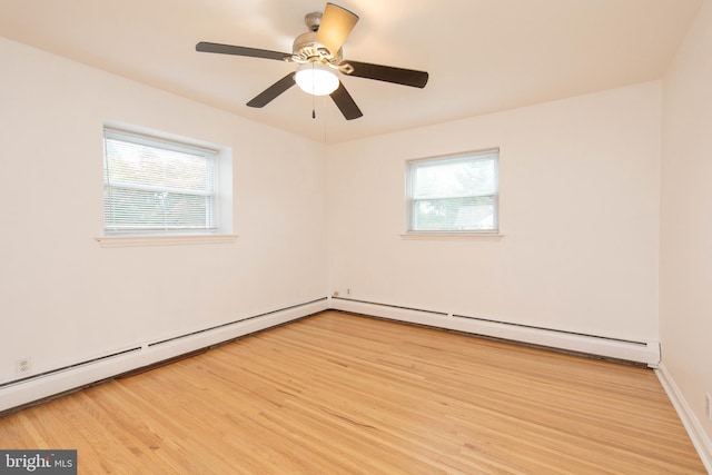 spare room with ceiling fan, light wood-type flooring, and a baseboard heating unit