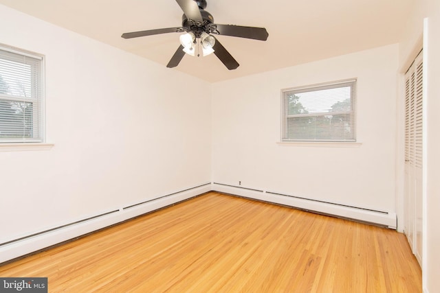 unfurnished bedroom featuring ceiling fan, light wood-type flooring, baseboard heating, and multiple windows