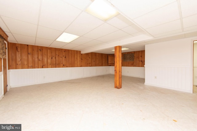 basement featuring wood walls and a paneled ceiling