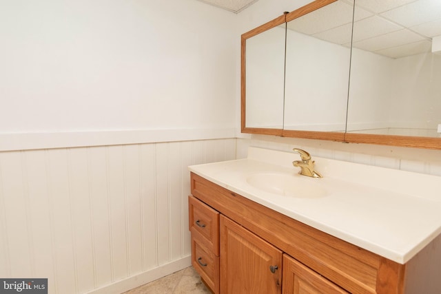 bathroom with a paneled ceiling, tile patterned flooring, and vanity