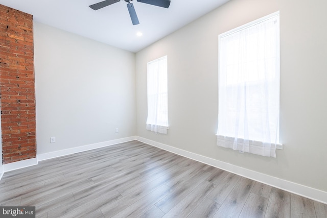 empty room featuring ceiling fan, light wood-type flooring, and plenty of natural light