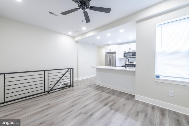 interior space featuring light wood-type flooring, sink, white cabinets, stainless steel appliances, and ceiling fan