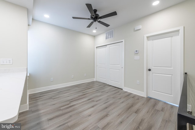 unfurnished bedroom with ceiling fan, light wood-type flooring, and a closet