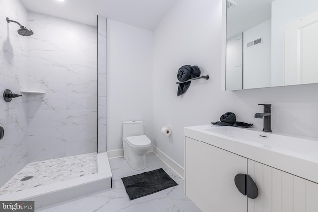 bathroom with a tile shower, vanity, and toilet