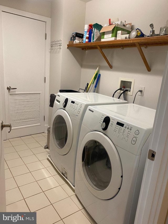 laundry area featuring washing machine and clothes dryer, light tile patterned floors, visible vents, and laundry area