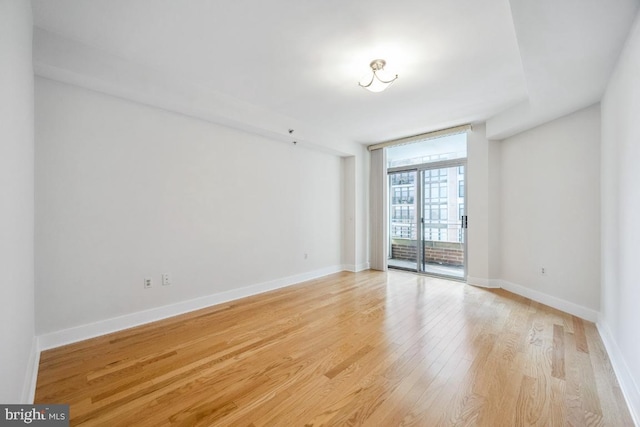 unfurnished room with baseboards, light wood-style flooring, and floor to ceiling windows