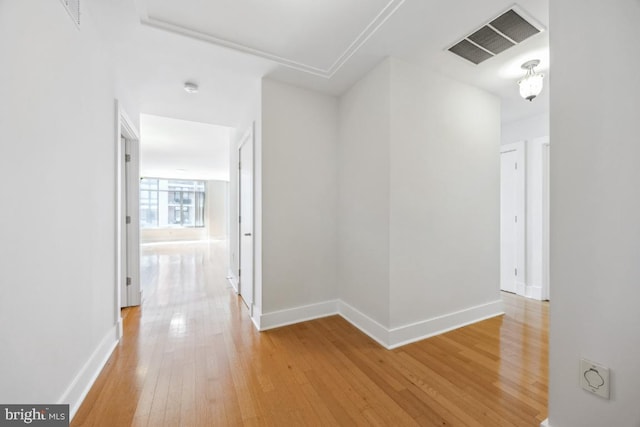 corridor with baseboards, light wood-type flooring, and visible vents